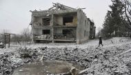 A local resident walks past a crater and a damaged residential building following a recent aerial bombardment in Kupiansk, Kharkiv region, on February 18, 2024, amid the Russian invasion of Ukraine. (Photo by SERGEY BOBOK / AFP)
