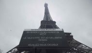 This photograph shows a board informing visitors that the Eiffel Tower, viewed in the background, is closed, during a strike of the Eiffel Tower's staff, over the financial management of the monument by the city, closing the monument to the public during the second week of the French school holidays, in Paris on February 20, 2024. Photo by GEOFFROY VAN DER HASSELT / AFP