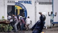 (File photo) A Police officer throws a rock as opposition supporters run into a opposition leader Martin Fayulu's party house during a demonstration in Kinshasa on December 27, 2023. (Photo by JOHN WESSELS / AFP)

