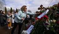 A woman lays flowers at the grave of late Russian opposition leader Alexei Navalny on the day of Russia's presidential election in Moscow on March 17, 2024. Photo Credit: NATALIA KOLESNIKOVA / AFP. 