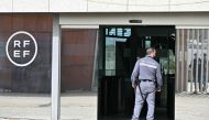 A security staff member stands as journalists wait outside the headquarters of the Spanish Royal Football Federation (RFEF) in Las Rozas de Madrid on March 20, 2024 during a police search. Photo Credit: JAVIER SORIANO / AFP.