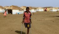 A picture taken on March 20, 2024, shows children who fled Khartoum and Jazira states in war-torn Sudan standing near tents at a camp for the internally displaced in southern Gadaref state. (Photo by AFP)