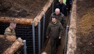  This handout photograph taken and released by Ukrainian Presidential press service on March 27, 2024, shows Ukraine's President Volodymyr Zelensky (centre) walking along trenches on the location of the 117th separate brigade of territorial defence in the Sumy region, amid the Russian invasion of Ukraine. (Photo by Handout / UKRAINIAN PRESIDENTIAL PRESS SERVICE / AFP) 
