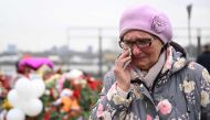 A woman reacts as she stands at a makeshift memorial in front of the Crocus City Hall in Moscow's northern suburb of Krasnogorsk on March 29, 2024, a week after a deadly attack by gunmen on a Moscow concert hall killed at least 143 people and wounded dozens more. (Photo by Natalia Kolesnikova / AFP)