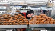 An employee serves pastry to a customer at a bakery in Tunis during the Muslim holy fasting month of Ramadan on March 29, 2024, amid a shortage of sugar supplies in the country. (Photo by FETHI BELAID / AFP)
