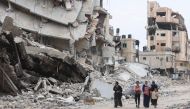 Palestinian women and children walk past the ruins of buildings destroyed by earlier Israeli bombardment in Gaza City on April 8, 2024. (Photo by AFP)