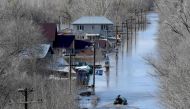A resident sails a rubber boat in a flooded residential area in the city of Orenburg on April 13, 2024. (Photo by Olga MALTSEVA / AFP)
