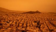 This photograph taken on April 23, 2024, in Athens shows a view of the city of Athens shrouded in haze, as southerly winds carried waves of dust to the city. (Photo by Angelos TZORTZINIS / AFP)
