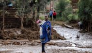 A woman carrying her baby on the back looks on near her house in a muddy area heavily affected by torrential rains and flash floods in Mai Mahiu, on April 29, 2024. Photo by LUIS TATO / AFP