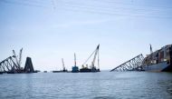 The cargo ship Dali (R) remains stuck in the wreckage of the Key Bridge as workers remove debris from the Patapsco River entrance to Baltimore Harbor on May 2, 2024, in Baltimore, Maryland. Photo by Brendan Smialowski / AFP