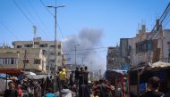Palestinians crowd a street as smoke billows nearby from Israeli strikes in Rafah in the southern Gaza Strip on May 7, 2024. (Photo by AFP)