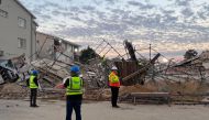 Officials are seen at the scene of a collapsed building in George on May 7, 2024. Photo by Willie van Tonder / AFP