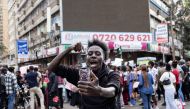 A man uses his phone to record a live video on social media while marching against the Finance Bill 2024 in downtown Nairobi on June 23, 2024. (Photo by Patrick Meinhardt / AFP)
