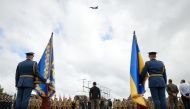 In this handout photograph taken and released by the Ukrainian Presidential Press Service on August 4, 2024, Ukraine's President Volodymyr Zelensky (center) watches a pair of F16 jets flying during Ukraine's Air Force Day celebrations at an undisclosed location. (Photo by Handout / UKRAINIAN PRESIDENTIAL PRESS SERVICE / AFP) 