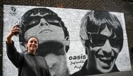 Fan Emily McShane, takes a photograph of a new street artwork depicting Oasis' Liam and Noel Gallagher, created by Manchester-based street artist Pic.One.Art. on the side of the Sifters Record store in Burnage, a suburb of Manchester, north-west England on August 27, 2024. Photo by Paul ELLIS / AFP

