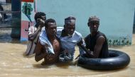 People help an elderly man wade through flood water in Maiduguri on September 12, 2024.  (Photo by Audu Marte / AFP)

