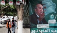 People walk past posters of Algeria's President Abdelmajid Tebboune outside an election campaign headquarters in Algiers on September 8, 2024. Photo by AFP.