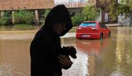 A boy holding a dog walks besides a street flooded by the Opava river on September 15, 2024 in Opava, Czech Republic. (Photo by Michal Cizek / AFP)

