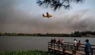 People watch a Spanish Canadair during a wildfire at Pateira de Fermentelos, Agueda in Aveiro on September 17, 2024. Photo by Patricia DE MELO MOREIRA / AFP.
