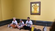 A handout picture from the Just Stop Oil climate campaign group shows three activists sitting on the floor under Vincent van Gogh's 