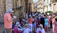 A group of tourists take a snack in a street of Valencia on July 5, 2024. Photo by Jose Jordan / AFP