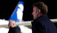 France's President Emmanuel Macron (R) looks on with the logo of Air Corsica on an aircraft in the background as he attends the Pope's departure ceremony at the Ajaccio airport, on the French island of Corsica, on December 15, 2024. (Photo by Ludovic MARIN / POOL / AFP)

