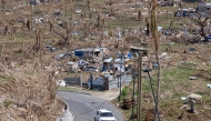 A car drives past destroyed homes in Pamandzi on the French Indian Ocean territory of Mayotte, after the cyclone Chido hit the archipelago on December 21, 2024. (Photo by PATRICK MEINHARDT / AFP)
