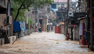 A resident wades through murky floodwaters following heavy rains in the Ndjili district of Kinshasa on April 6, 2025. Photo by Hardy BOPE / AFP