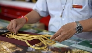 An employee handles gold jewelry for customers at Hua Seng Heng gold traders in Chinatown in Bangkok on April 9, 2025. (Photo by Lillian SUWANRUMPHA / AFP)
