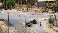 Sudanese men ride on a motorcycle past destroyed military vehicles in front of a hospital in Khartoum on April 28, 2025. (Photo by AFP)
