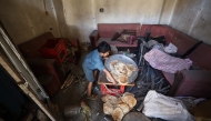 A Palestinian boy salvages bread from a makeshift bakery hit in Israeli strikes at the Nuseirat refugee camp in the central Gaza Strip on May 8, 2025. (Photo by Eyad BABA / AFP)