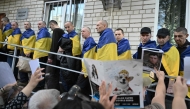 Freed Ukrainian POW upon their arrival after a prisoner exchange in the Chernygiv region look at a people which holds portraits of their missing or captured relatives and friends on May 23, 2025. (Photo by Genya Savilov / AFP)
