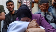A woman mourns over the body of a victim who was killed during overnight Israeli bombardment as she sits at al-Shifa hospital in Gaza City on June 4, 2025. (Photo by Omar Al-Qattaa / AFP)