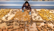 A handout picture released by the Museum of London Archaeology (MOLA) on June 19, 2025 shows MOLA senior building material specialist Han Li laying out Roman plaster fragments from The Liberty development site in Southwark, south London. Photo by Handout / Museum of London Archaeology (MOLA) / AFP