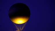 The Paris 2024 Olympic cauldron tethered to a balloon, designed by French designer Mathieu Lehanneur, flies above the Tuileries garden at sunset during France's annual street music festival, the Fete de la Musique, in Paris on June 21, 2025. (Photo by ROMAIN PERROCHEAU / AFP)