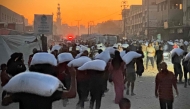 Men walk carrying sacks of flour that were taken from a raided truck carry sacks of flour after raiding a truck that was carrying foodstuffs, in Khan Yunis in the southern Gaza Strip on July 22, 2025. (Photo by AFP)