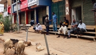 People sit on stairs outside shuttered stores at al-Hurriya street, a popular destination to buy electric home appliances before the Sudan war, as the shopping street reopens at al-Arabi market in Khartoum on July 15, 2025. (Photo by AFP)
