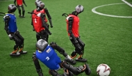 Humanoid robots vie for the ball during an exhibition football match ahead of the World Humanoid Robot Games in Beijing on August 4, 2025. (Photo by Pedro Pardo / AFP)