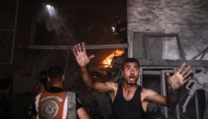 A Palestinian man reacts as firefighters battle a blaze inside a shop, following an Israeli strike that hit Gaza City's southern al-Zeitoun neighbourhood on August 8, 2025. Photo by BASHAR TALEB / AFP