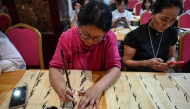 The photo taken on July 23, 2025 shows people learning Nushu calligraphy in a hotel conference room repurposed as a temporary classroom in Jiangyong county, southern China's Hunan province.(Photo by Jade Gao / AFP) 