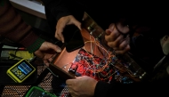Men repair a disused computer during the 3rd Federal Cyberciruja Meeting in Buenos Aires, on August 16, 2025. Photo by Luis ROBAYO / AFP