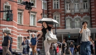 People cross a street outside Tokyo Station on a hot day in Tokyo on August 27, 2025. (Photo by Yuichi Yamazaki / AFP)