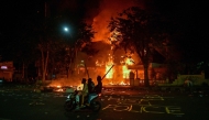 Protesters rides a motorcycle in front of a police headquarters that was burned and looted during demonstrations in Surabaya on August 31, 2025. Photo by Juni KRISWANTO / AFP