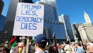 Protesters hold signs reading 