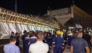 First responders and onlookers gather in front of a bridge under construction, after a section of it collapsed, killing two people and injuring others, in Karbala in southern Iraq late on September 6, 2025. Photo by Salman AMIN / AFP