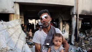 An injured man carries a toddler as others search for their belongings amid the rubble, in the al-Farabi school turned shelter for displaced Palestinians, after it was hit by an Israeli strike, in Gaza City in the northern Gaza Strip on September 7, 2025. (Photo by Omar AL-QATTAA / AFP)