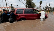 Firefighters and a member of the National Guard assist a driver stranded in floodwater after heavy rains caused the Arroyo Seco River to overflow in Tlajomulco de Zٌْiga, Jalisco, Mexico, on September 9, 2025. (Photo by ULISES RUIZ / AFP)
