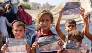 Children hold some of the leaflets dropped by the Israeli military, urging evacuation to al-Mawasi in the southern Gaza Strip, as occupation forces step attacks, on September 12, 2025. (Photo by Omar Al-Qattaa / AFP)