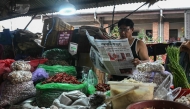 A vegetable vendor reads a Nepali-language newspaper on a roadside in Kathmandu on September 12, 2025. (Photo by Arun Sankar / AFP)
 