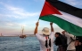 A man waves a Palestinian flags to other activists and human rights defenders riding aboard a vessel departing from Tunisia's northern port of Bizerte on September 14, 2025 to join the last boats taking part in the Global Sumud Flotilla. (Photo by Mohamed Fliss / AFP)